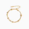 Three-strand gold-plated bracelet with clustered ball beads and adjustable clasp on cream background