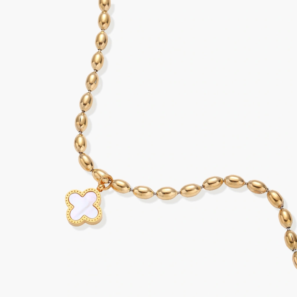 18K gold-plated oval bead bracelet with a four-leaf clover charm in mother-of-pearl or black enamel, adjustable lobster clasp, on white background.