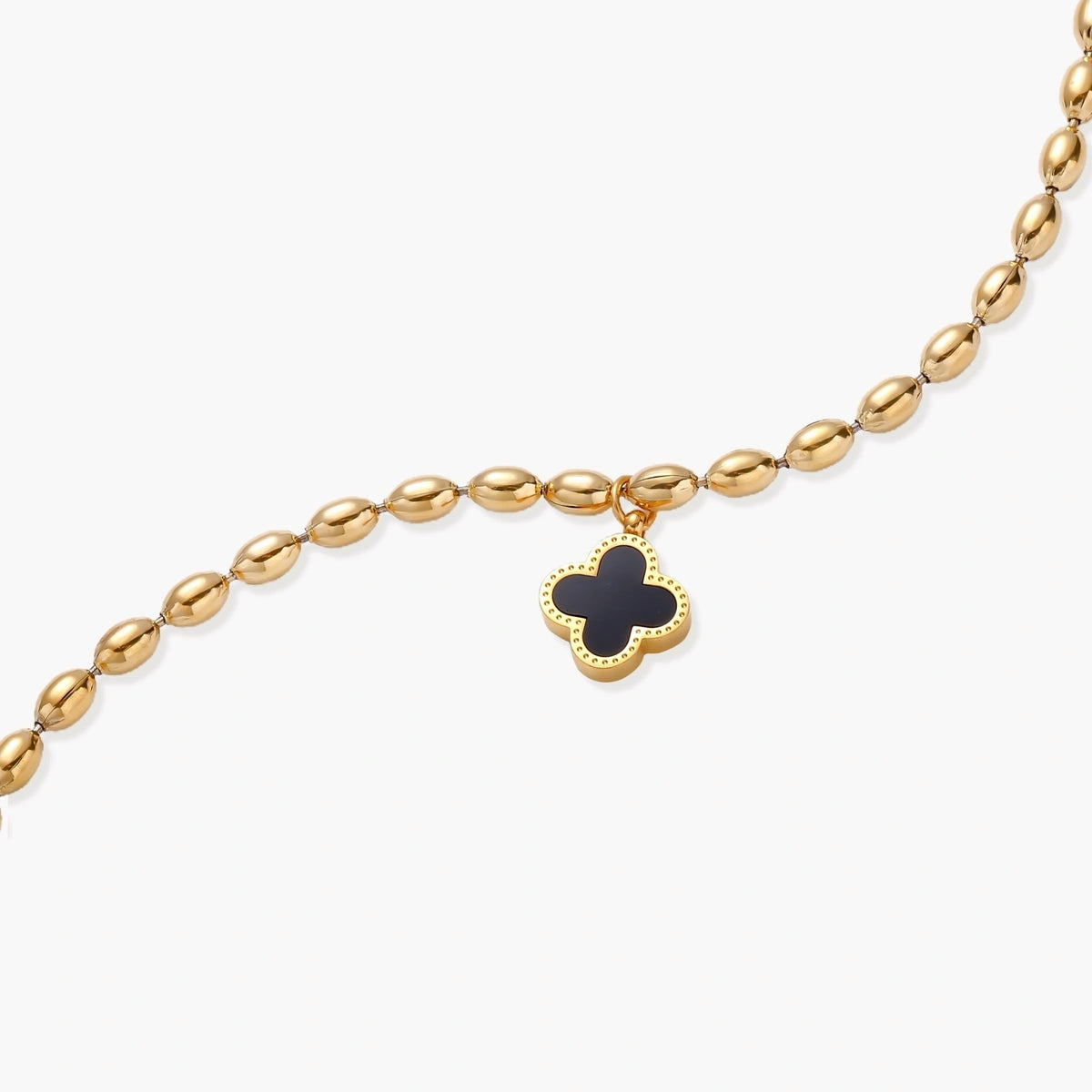 18K gold-plated oval bead bracelet with a four-leaf clover charm in mother-of-pearl or black enamel, adjustable lobster clasp, on white background.