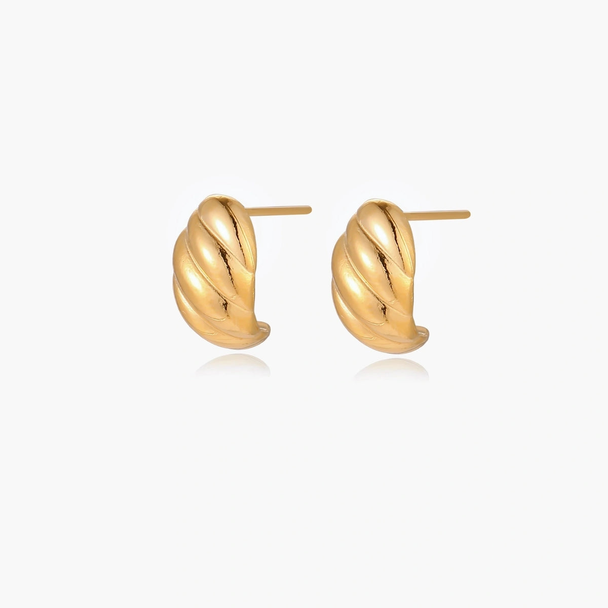 Chunky gold twisted rope huggie hoops with diagonal grooves and high-polish finish on cream background