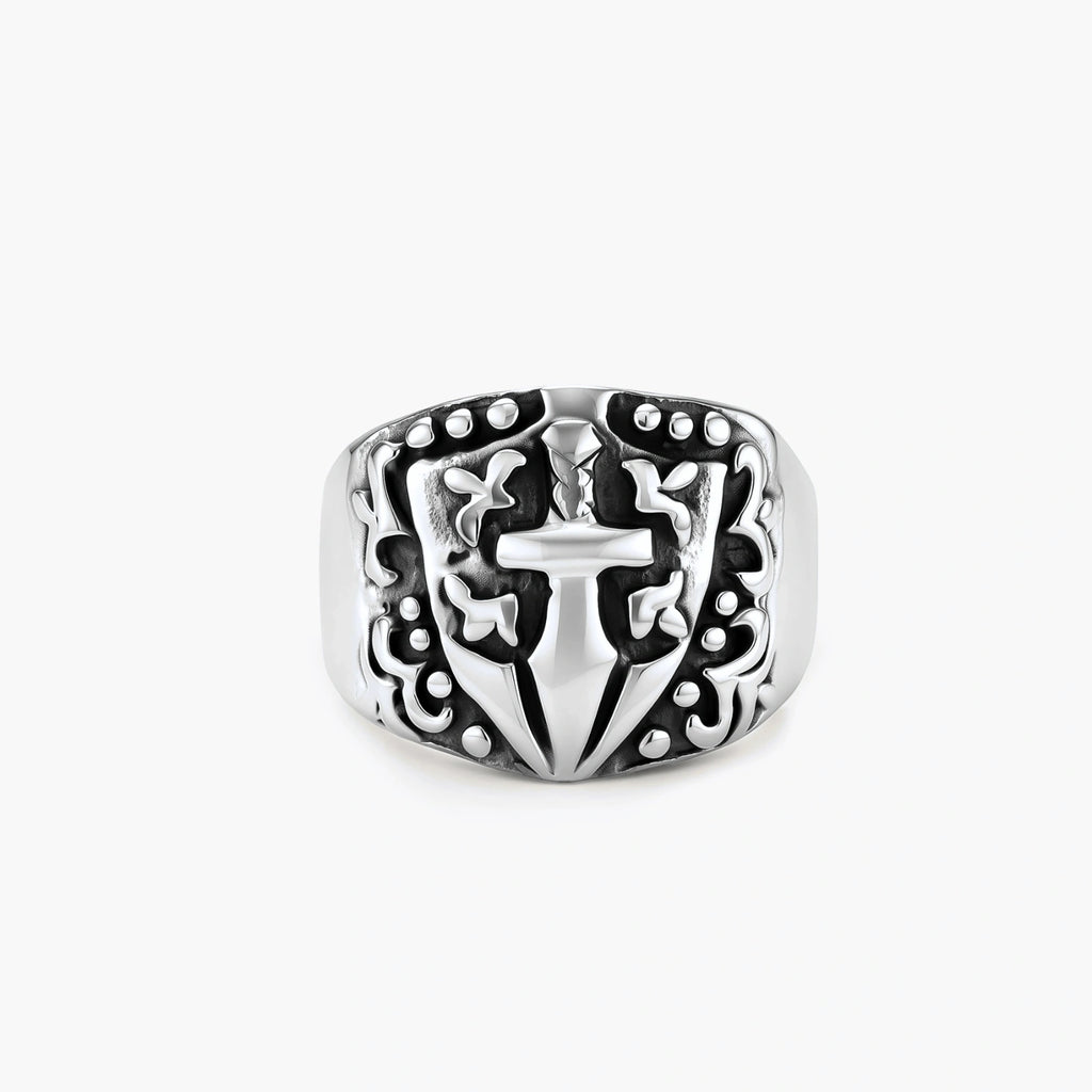 Silver 316L stainless steel men's signet ring with raised knight shield, cross motif, and ornate blackened scrollwork detailing.